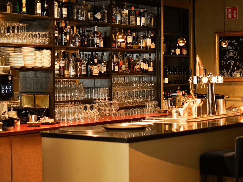 Sfeervolle hotelbar in Amrâth Berghotel Amersfoort met een goed gevulde drankencollectie, stijlvolle glazen opstelling en warme verlichting boven een elegante bar.
