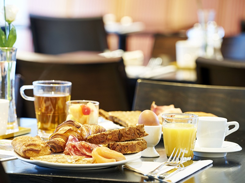 Een ontbijtbord met croissants, brood, vleeswaren, zalm, een gekookt ei, jus d'orange en thee in Amrâth Berghotel 