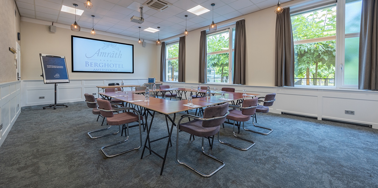 Meeting room in Amrâth Berghotel Amersfoort with wooden tables and comfortable chairs with plenty of daylight
