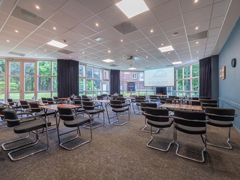 A meeting room in Amrâth Berghotel Amersfoort equipped with wooden tables and chairs with plenty of natural light